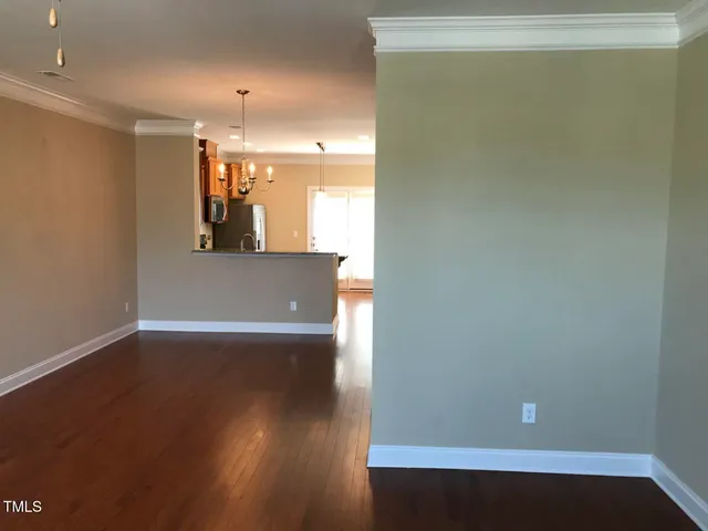 an empty room with wooden floor and fan