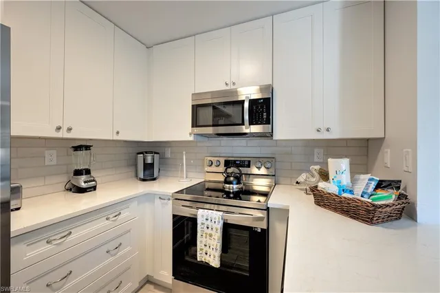 a kitchen with granite countertop white cabinets and stainless steel appliances
