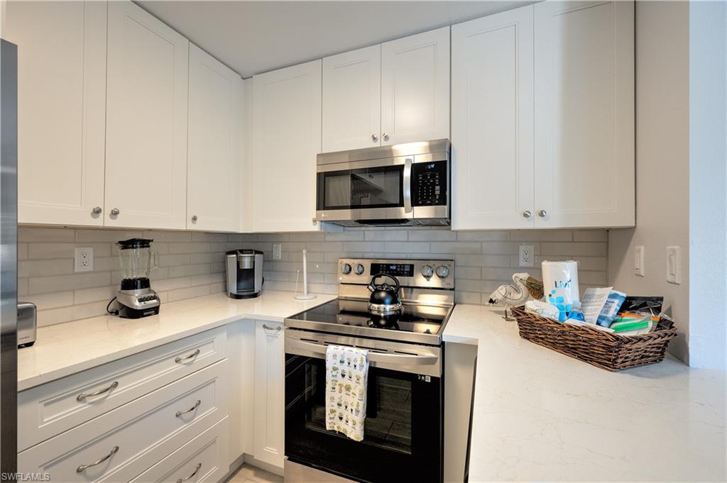 655 8th Avenue South, Unit 3 Naples, FL 34102 - Photo 4 of 48 a kitchen with granite countertop white cabinets and stainless steel appliances