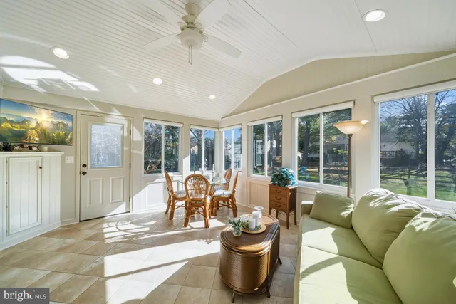 a living room with furniture a flat screen tv and floor to ceiling window