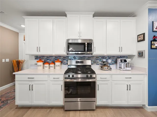 a kitchen with white cabinets and appliances
