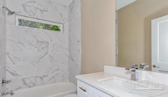 a bathroom with a granite countertop sink and a bathtub