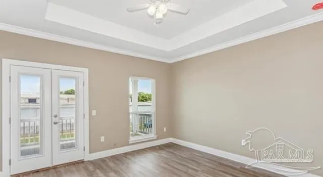 an empty room with wooden floor fan and windows
