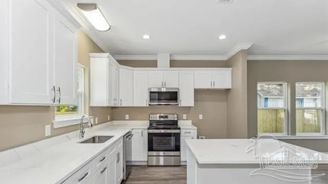 a kitchen with granite countertop a sink a stove top oven a counter space and cabinets