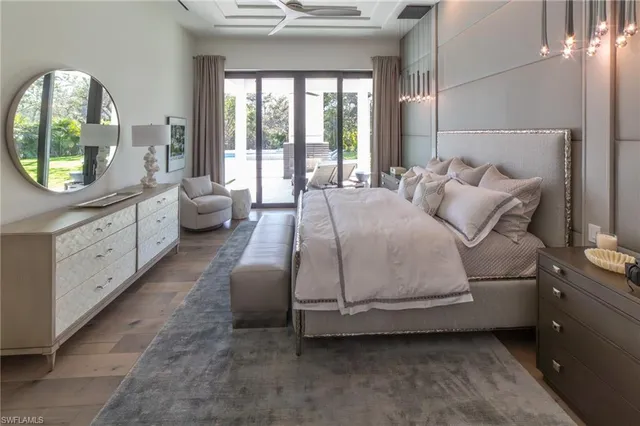 a bedroom with a bed a mirror on table and a large window