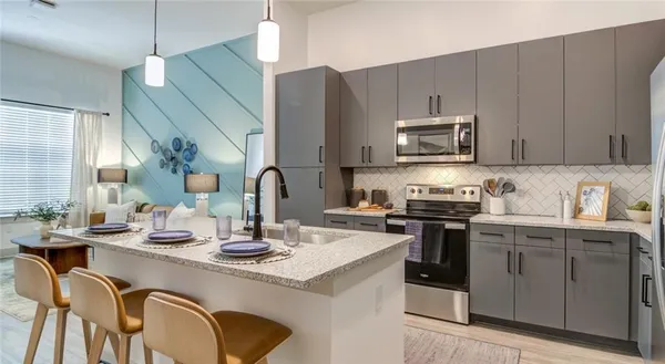 a kitchen with stainless steel appliances granite countertop a sink a stove a refrigerator cabinets and chairs