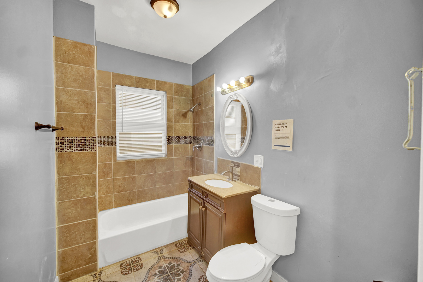 1 East 114th Street Chicago, IL 60628 - Photo 13 of 25 a bathroom with a toilet a sink a mirror a bathtub and shower