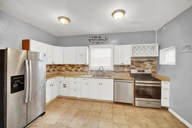 a kitchen with stainless steel appliances granite countertop a stove a refrigerator and a sink