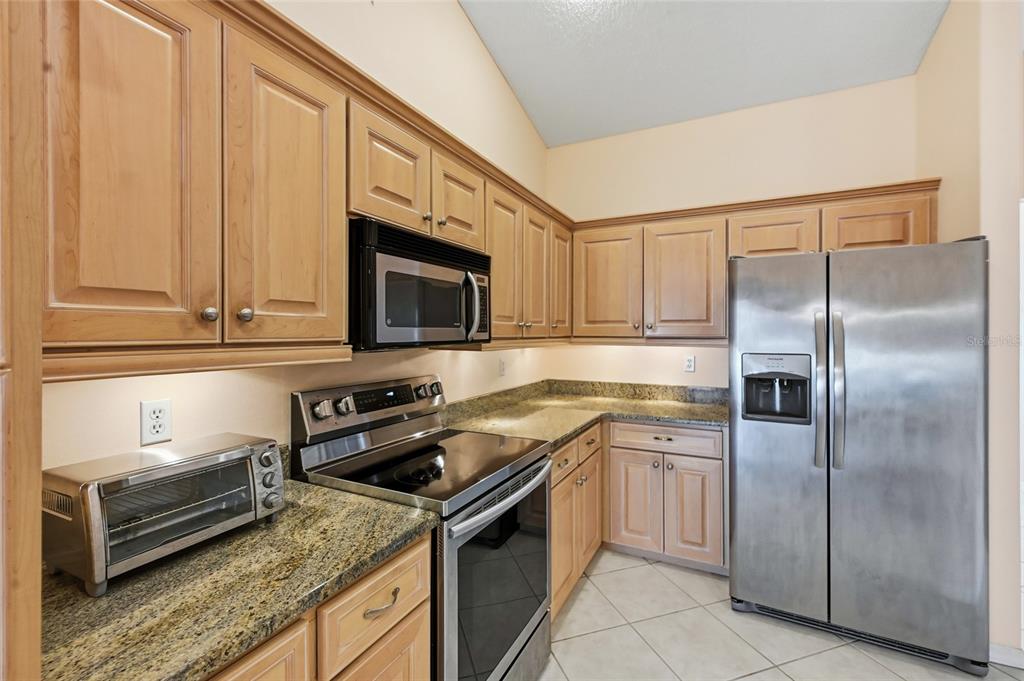 3732 Surrey Lane Sarasota, FL 34235 - Photo 18 of 35 a kitchen with stainless steel appliances granite countertop a stove microwave and refrigerator