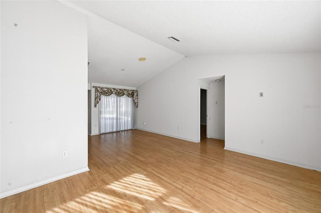 3732 Surrey Lane Sarasota, FL 34235 - Photo 3 of 35 a view of an empty room with wooden floor and a window