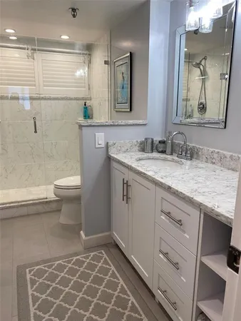 a bathroom with a granite countertop sink a toilet and a mirror