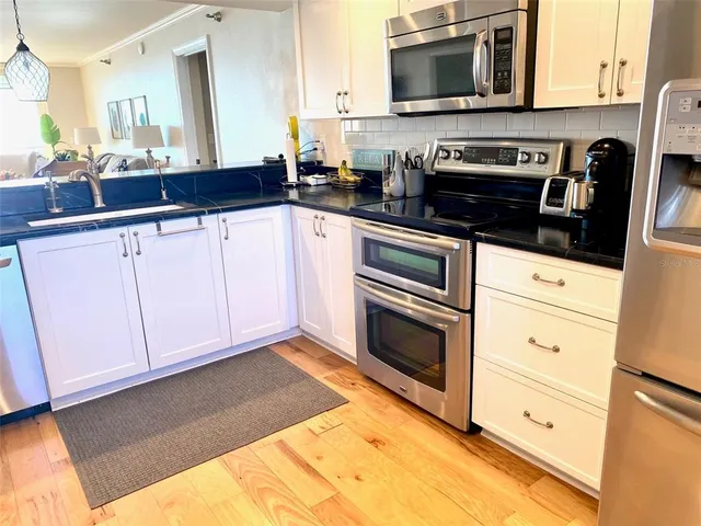 a kitchen with granite countertop white cabinets stainless steel appliances and a sink