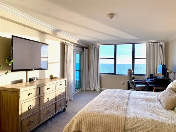a bedroom with a bed a large window and flat screen tv