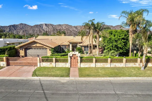 a view of a house with a yard and palm trees