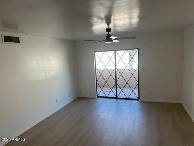 an empty room with wooden floor chandelier fan and windows