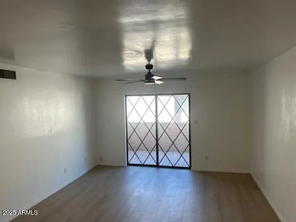 an empty room with wooden floor chandelier and windows