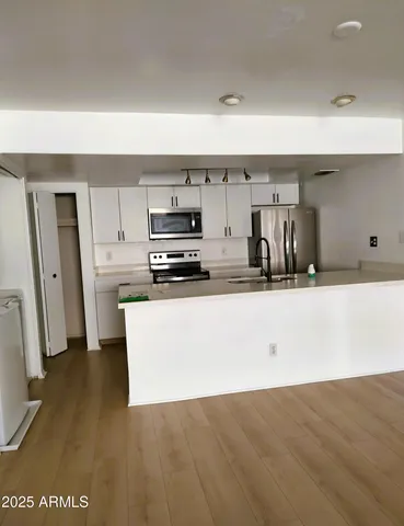 a kitchen with stainless steel appliances a refrigerator a stove a sink and white cabinets