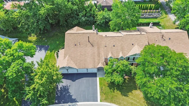 an aerial view of a house with a yard and trees all around