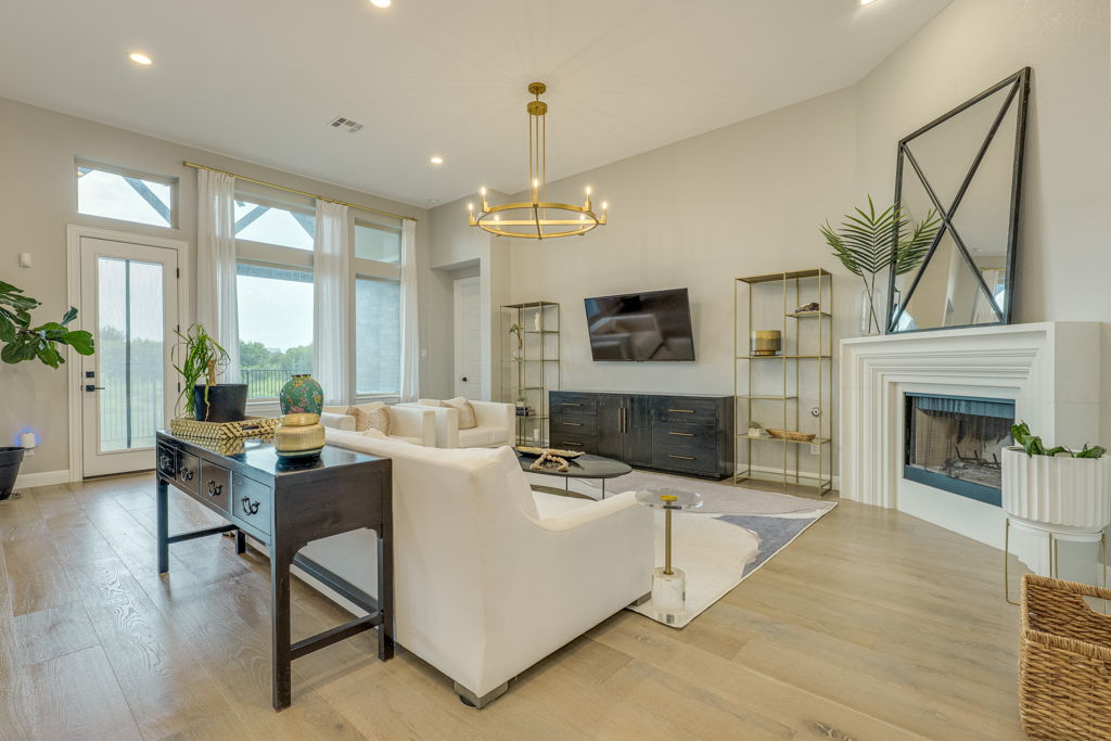 4209 Brean Down Road Pflugerville, TX 78660 - Photo 10 of 31 A refined living space showcases light wood flooring and a classic white fireplace, bathed in natural light from tall windows.