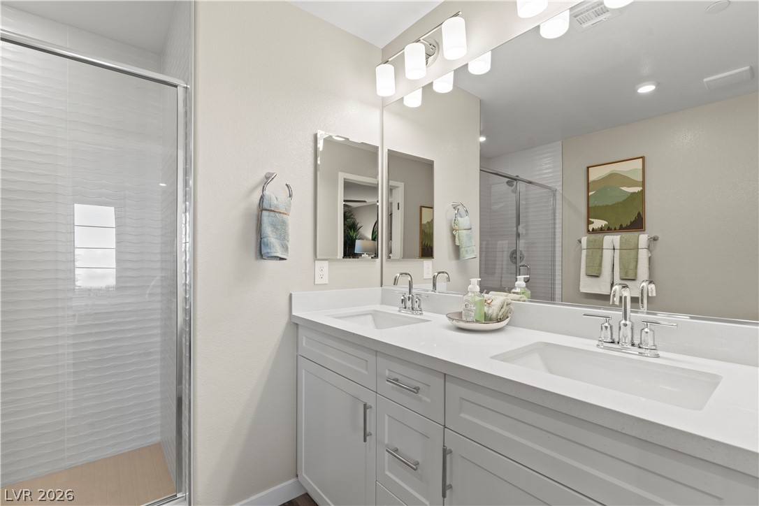 313 Keyboard Place Henderson, NV 89015 - Photo 5 of 22 Dual vanities with chrome fixtures and a spacious walk-in shower elevate this contemporary bathroom.