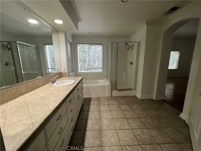 a spacious bathroom with a granite countertop sink a mirror and a bathtub