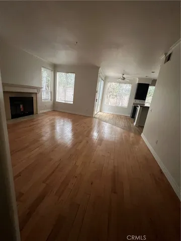 an empty room with wooden floor fireplace and windows