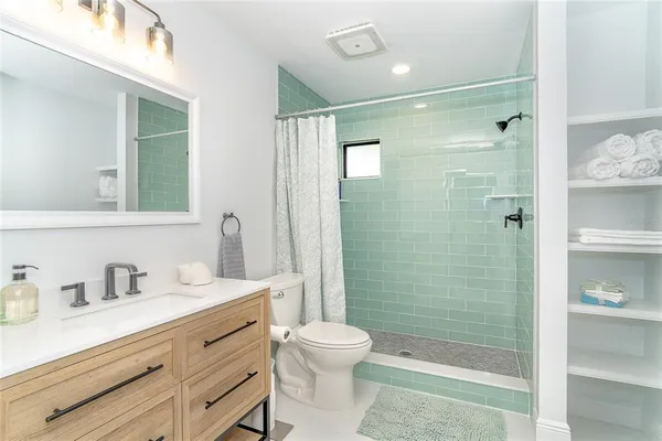 a bathroom with a shower sink vanity mirror and toilet