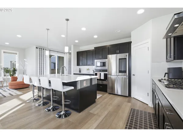 a dining hall with stainless steel appliances kitchen island a table chairs stove and kitchen view