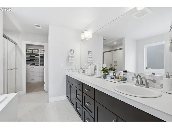 a spacious bathroom with a double vanity sink a large mirror a bathtub and shower