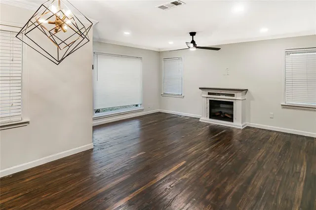 an empty room with wooden floor fireplace and windows
