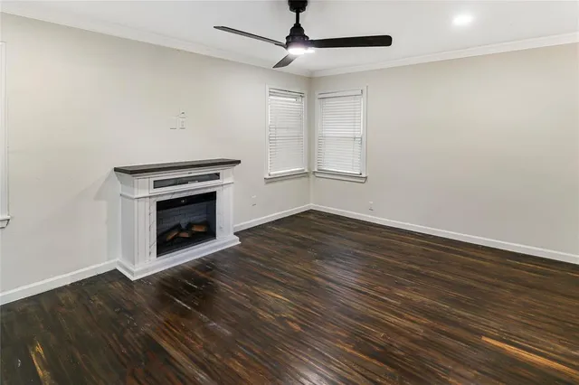 a view of a livingroom with wooden floor a ceiling fan and staircase