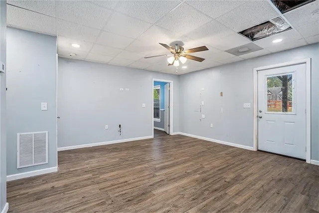 an empty room with wooden floor and ceiling fan