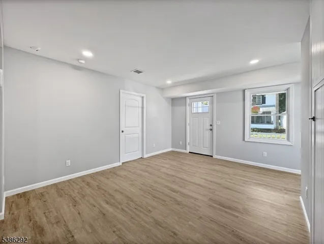 a view of an empty room with window and wooden floor