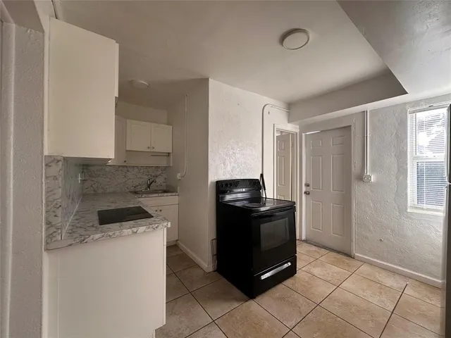 a kitchen with granite countertop a refrigerator and a stove top oven