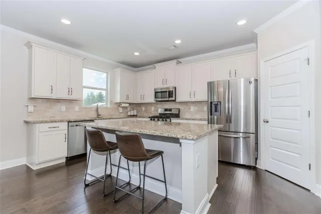 a kitchen with stainless steel appliances granite countertop a refrigerator and a stove top oven