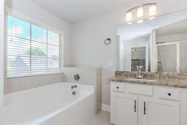 a bathroom with a bathtub a sink a vanity a window and a mirror