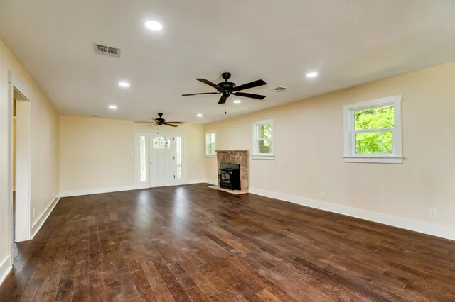 an empty room with ceiling fan and windows