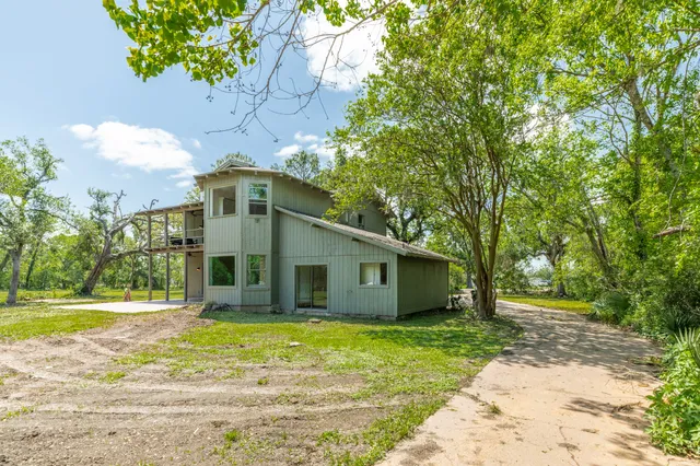 a view of a white house with a big yard and large trees