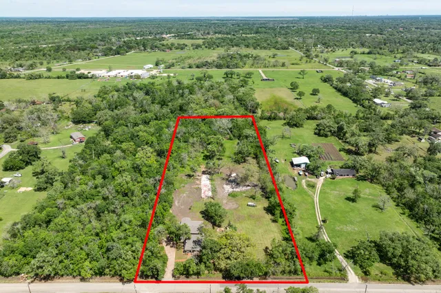 an aerial view of residential houses with outdoor space and trees