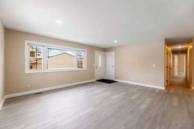 an empty room with wooden floor and windows
