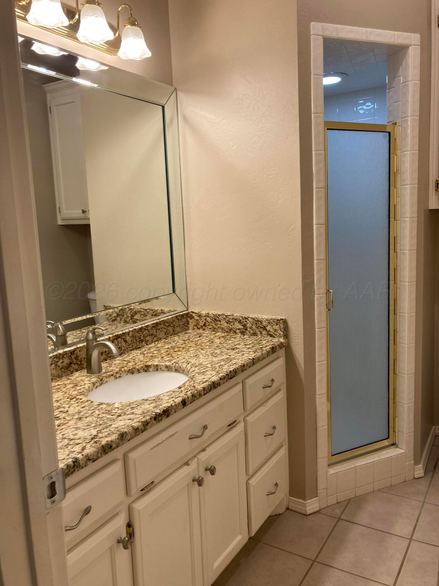 3509 West Point Drive Amarillo, TX 79121 - Photo 8 of 10 a bathroom with a granite countertop sink and a mirror