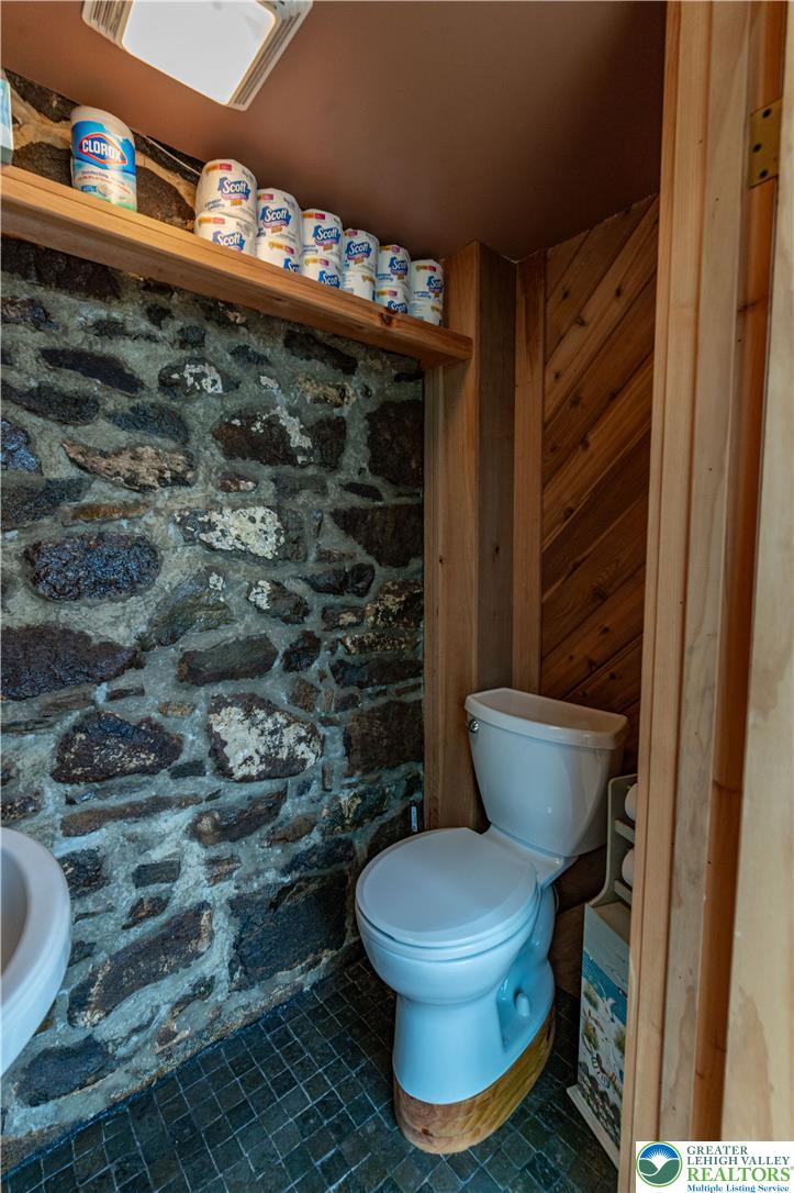 2485 Hieter Road Quakertown, PA 18951 - Photo 56 of 97 A rustic water closet, featuring stone walls and wood paneling, provides a unique and cozy experience.