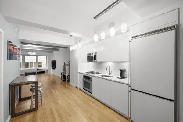 a kitchen with kitchen island a stove a refrigerator and a dining table with wooden floor