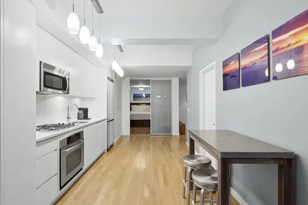 a kitchen with granite countertop a stove top oven a sink dishwasher and a refrigerator with wooden floor