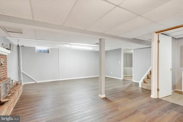 an empty room with wooden floor fireplace and staircase