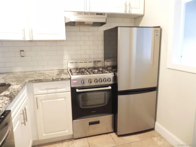 a kitchen with stainless steel appliances granite countertop a refrigerator a stove and a sink