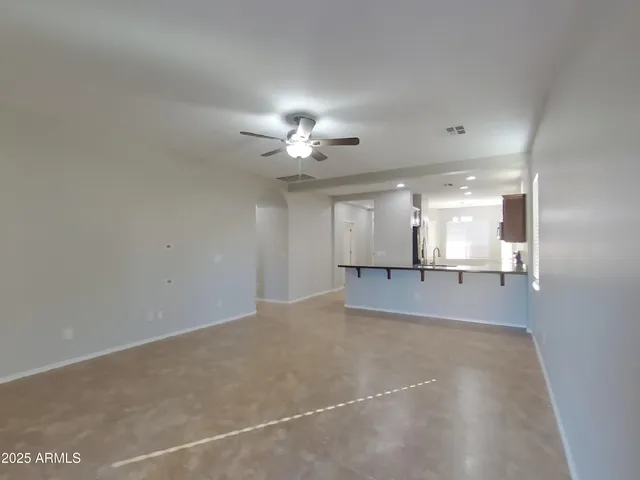 an empty room with chandelier fan and windows
