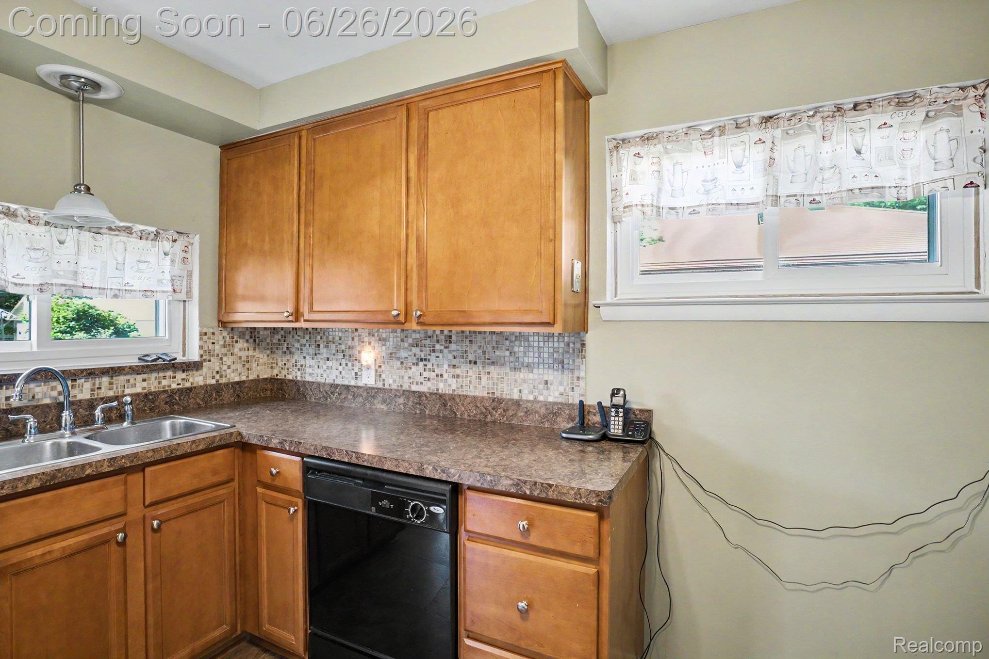 1209 Massoit Road Clawson, MI 48017 - Photo 11 of 25 Kitchen featuring wood cabinetry, mosaic tile backsplash, black dishwasher, double basin sink, and pendant lighting