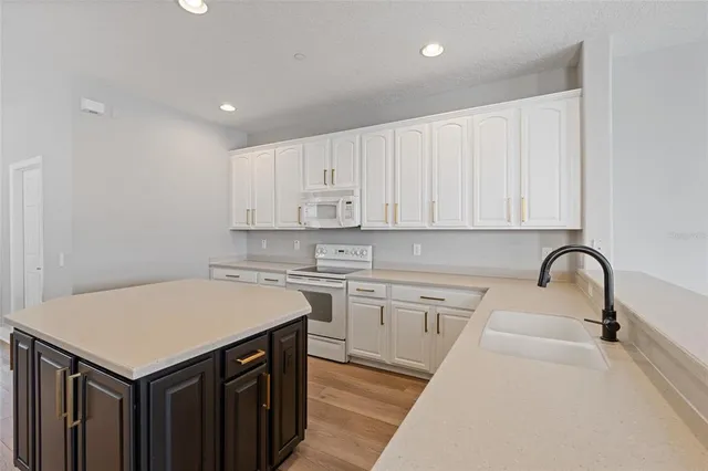 a kitchen with a sink a stove cabinets and wooden floor