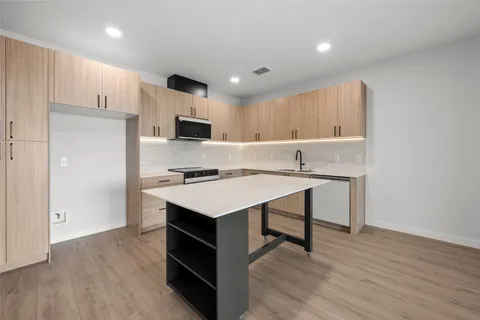 a kitchen with kitchen island a cabinets a sink and a refrigerator